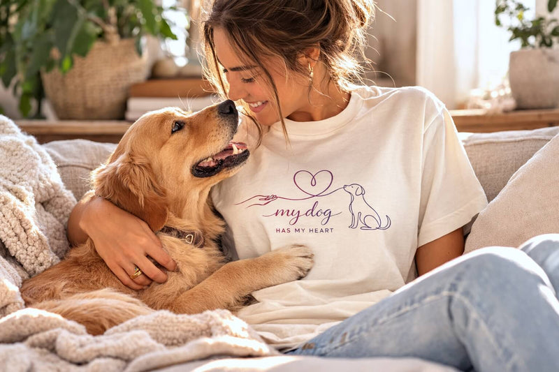 Dog mom cuddling her golden retriever while wearing a 'My Dog Has My Heart' dog lover t-shirt in a cozy living room