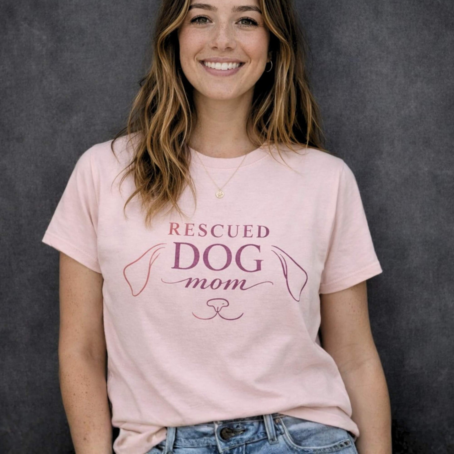 Woman wearing soft pink “Rescued Dog Mom” t-shirt with minimalist dog line design, premium dog lover apparel by Zevinity