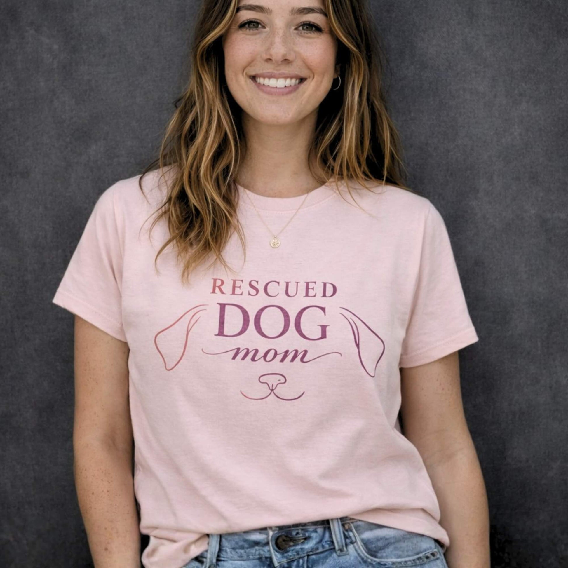 Woman wearing soft pink “Rescued Dog Mom” t-shirt with minimalist dog line design, premium dog lover apparel by Zevinity