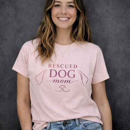Woman wearing soft pink “Rescued Dog Mom” t-shirt with minimalist dog line design, premium dog lover apparel by Zevinity